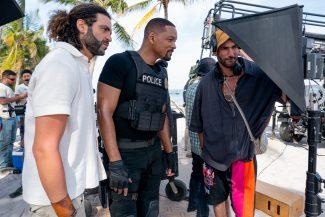 Adil El Arbi, Will Smith and Bilall Fallah looking at a camera monitor on set.